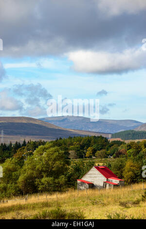 Red-roofed wooden hut in a rural area of the Cairngorms, Scotland under a partly cloudy autumn sky Stock Photo