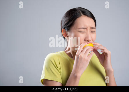 Young woman eating lemon Stock Photo