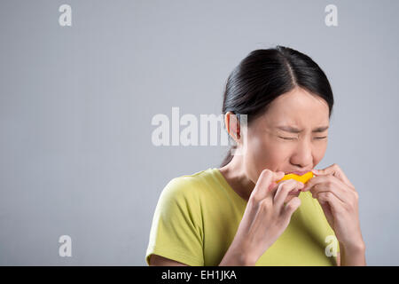 Young woman eating lemon Stock Photo
