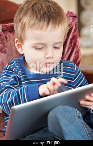Boy Sitting On Sofa And Playing With Digital Tablet Stock Photo