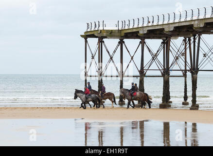 Saltburn by the sea, UK. 5th March, 2015. UK Weather: Horseriders under Saltburn`s Victorian pier on an overcast but noticibly milder Thursday morning in the north east of England. Credit:  ALANDAWSONPHOTOGRAPHY/Alamy Live News Stock Photo