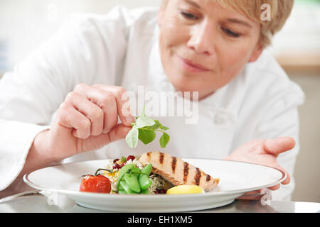 Chef Adding Garnish To Meal In Restaurant Kitchen Stock Photo