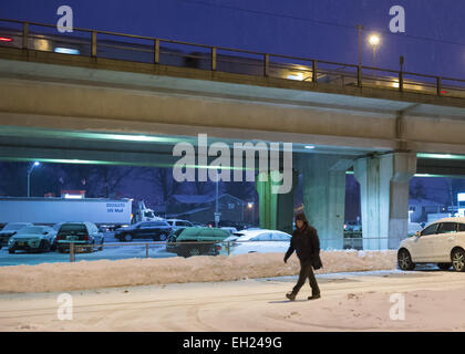 New York, New York, USA. 3rd Mar, 2015. During peak of evening commute, a Long Island Rail Road travels on the elevated train platform as snow falls at Merrck LIRR train station, of MTA, Mass Transit Authority, as a man walks through the snowy parking lot, and a large long white truck carrying US MAIL is seen traveling on Sunrise Highway, south of the tracks. The area is under a Winter Weather Advisory, and a Winter Storm Watch for hazardous conditions is in effect from Wednesday night to Thursday night in Long Island, New York City and other nearby areas of the northeast (Credit I Stock Photo