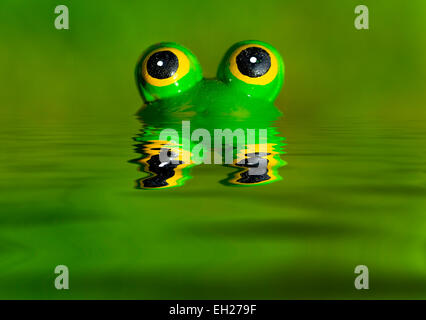 A green ceramic frog peeking out from a digitally created pool of water Stock Photo