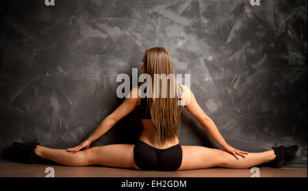 beautiful young blond woman doing fitness in the gym. stretches the legs on the twine Stock Photo