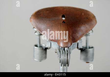 old-fashioned vintage leather bike saddle with metal spring Stock Photo