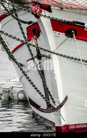 The bow of an old sailing ship with old anchor and neatly painted in red and white. Stock Photo