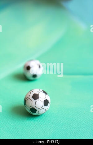 Toy soccer footballs on green canvas background. Stock Photo