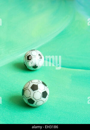 Toy soccer footballs on green canvas background. Stock Photo