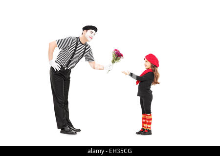 Full length portrait of a mime artist giving flowers to a little girl isolated on white background Stock Photo