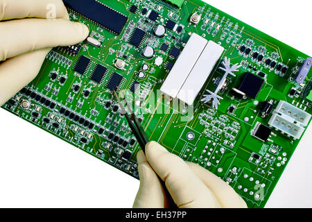Closeup of Computer circuit board cpu inspection with gloved hands and forceps isolated on white with selective focus. Stock Photo