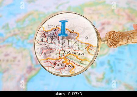 Blue tack on map of the world with magnifying glass looking in on Tbilisi, Georgia Stock Photo