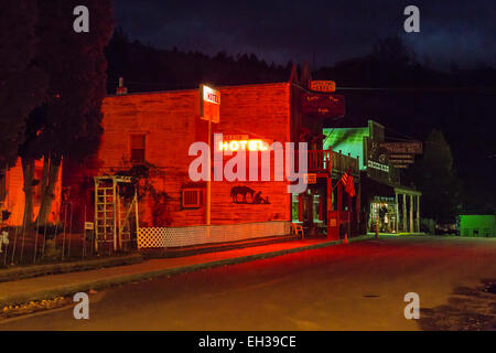 Classic western streetscape at night, with a neon Oregon Hotel sign lighting the sides of a building, in Mitchell, Oregon, USA Stock Photo