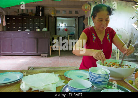 Vietnamese woman making rice-paper rolls Stock Photo