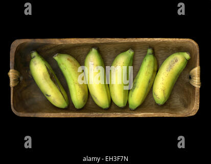 Ripe tropical bananas on a wooden board isolated on black background Stock Photo