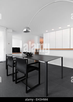 interior view of a modern dining room with dining table in foreground overlooking on the kitchen with kitchen island Stock Photo