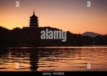 Black silhouette of traditional Chinese pagoda on orange evening sky background. Coast of West Lake. Famous park in Hangzhou cit Stock Photo