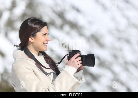 Tourist woman photographing on winter holidays with a snowy mountain in the background Stock Photo