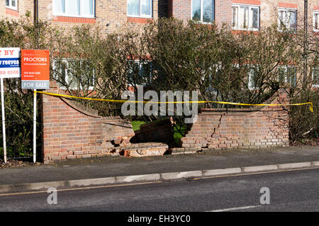 A damaged brick wall with warning tape in front in south London. Stock Photo