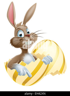 Cartoon happy Easter bunny rabbit in an Easter egg pointing Stock Photo