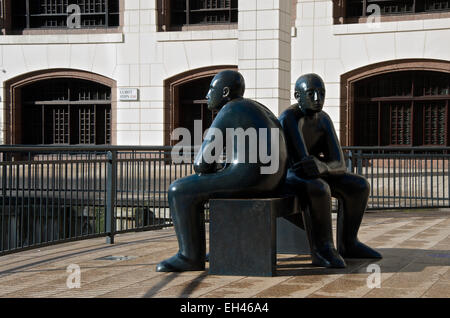 Sculpture of two figures on a bench facing in opposite directions. Stock Photo