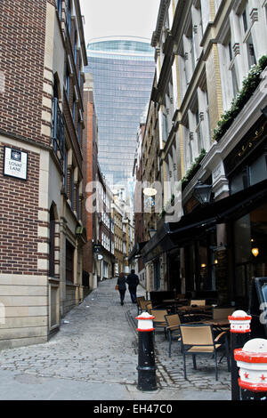 A couple walking down an old narrow street, Lovat Lane London EC3 with a new skyscraper in the distance. Stock Photo