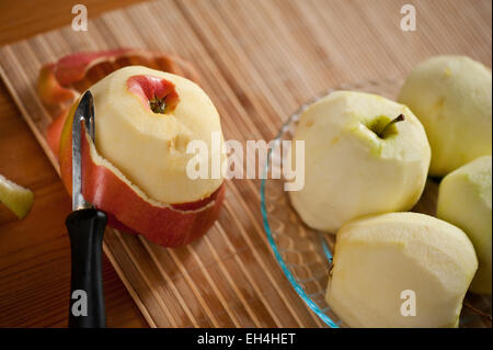 Peeling fresh red apple lying on bamboo mat Stock Photo