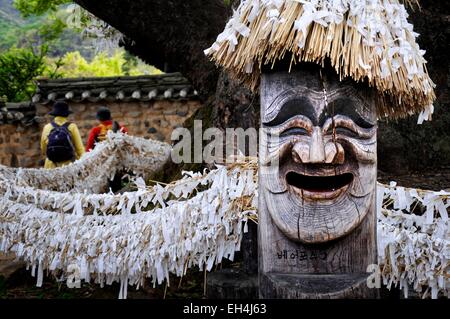 South Korea, North Gyeongsang Province (Gyeongsangbuk-do), Andong, Hahoe Folk Village listed as World Heritage by UNESCO, 600 years old Sinmok, a large and very old tree with a Jangseung, wooden totem pole with a laughing human face carved and a hat Stock Photo