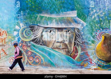 Ecuador, Imbabura, Atuntaqui, Ecuadorian busy modern woman in front of a wall graffiti depicting a traditional Andean woman Stock Photo