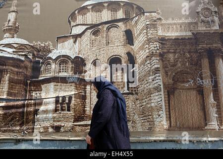 Turkey, Istanbul, Beyoglu, Taksim District, Taksim Square, Turkish woman passing a wall poster of a mosque Stock Photo