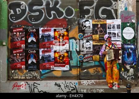 Turkey, Istanbul, SIraselviler Caddesi, street performer dressed as clowm playing the accordion in front of posters Stock Photo