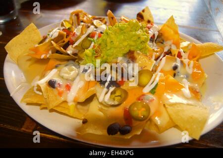 macho nachos- a mound of corn tortilla chips over fried beans ,  cheese blend, pickled jalopenos,etc Stock Photo