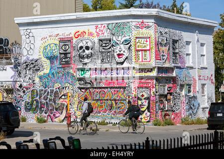 Canada, Quebec, Montreal, the Plateau-Mont-Royal, a former convenience store, temporarily abandoned house decorated with graffitis, cyclists Stock Photo