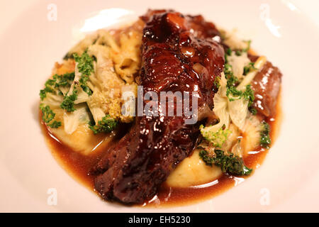 A plate of slow cooked beef cheeks, savora mash, rainbow kale and celeriac straw. Stock Photo