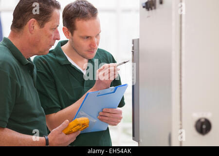 Senior technician and junior technician repairing agriculture machinery in a greenhouse Stock Photo