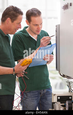 Senior technician and junior technician repairing agriculture machinery in a greenhouse Stock Photo