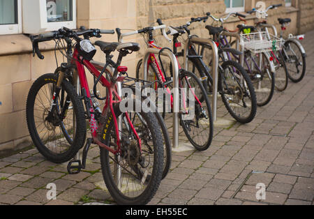 Row of bicycles on bike racks parked on pavement, Bristol, UK Stock Photo