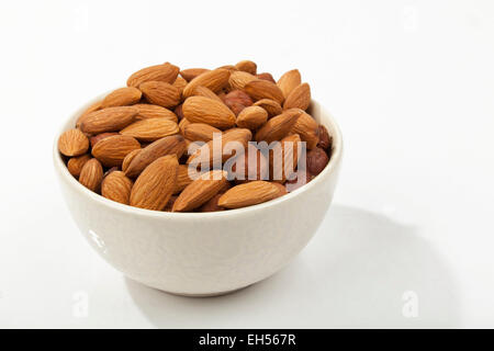almonds in a white bowl on white table Stock Photo