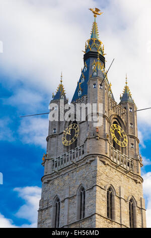 View from the bottom up to the tower Belfry with a clock and a statue of a dragon in Ghent, Belgium. Stock Photo