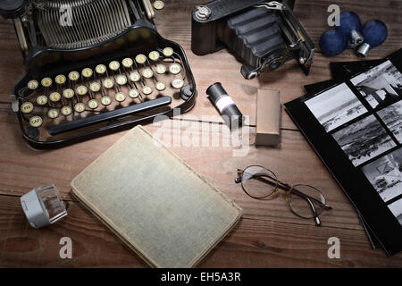 Closeup of a retro photography still life with typewriter, folding camera, loupe, roll film, flash bulbs, contact prints and boo Stock Photo