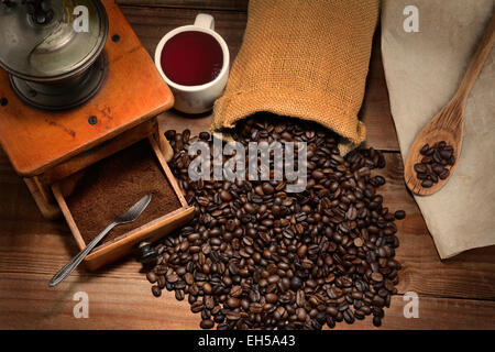 Coffee Still Life with antique grinder and spilled beans on a rustic wood table. Horizontal format with warm tones. Stock Photo