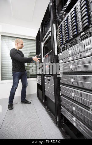 It engineer / consultant wokring and install / inserts a router / switch in a data rack. Shot in a data center. Stock Photo