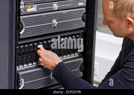It engineer / consultant working in a data center. This enclosure is a SAN (storage area network) and servers at the top. Stock Photo