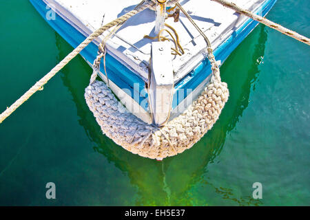 Old wooden fishing boat prow in green sea water Stock Photo