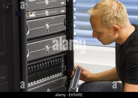 It engineer / consultant working in a data center. This enclosure is a SAN (storage area network) and servers at the top. Stock Photo