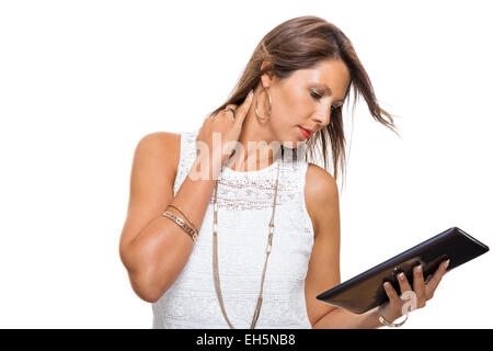 Attractive young business woman standing chatting on a mobile while simultaneously reading a tablet computer with a smile, isolated on white Stock Photo