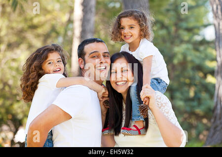 happy hispanic people parents giving children piggyback Stock Photo - Alamy