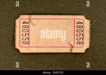 Old torn blank movie or raffle ticket on a mottled brown paper background. Stock Photo