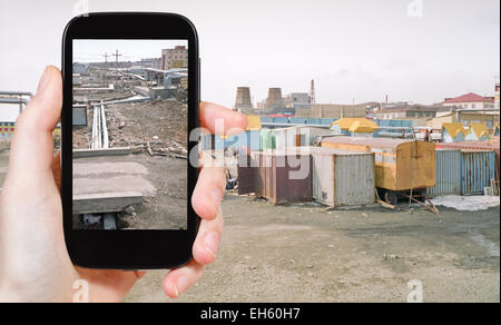 travel concept - tourist taking photo of street market and pipeline in Anadyr town on mobile gadget, Chukotka, Russia Stock Photo