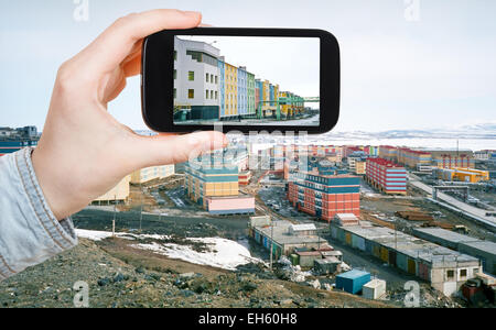 travel concept - tourist taking photo of Anadyr town on mobile gadget in spring, Chukotka, Russia Stock Photo